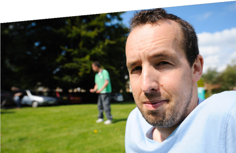 Photograph opf a man sitting outside in a park.