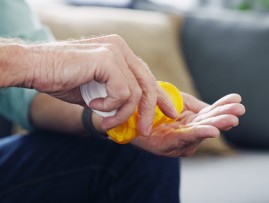 Photograph of a man taking some tablets out of a bottle.